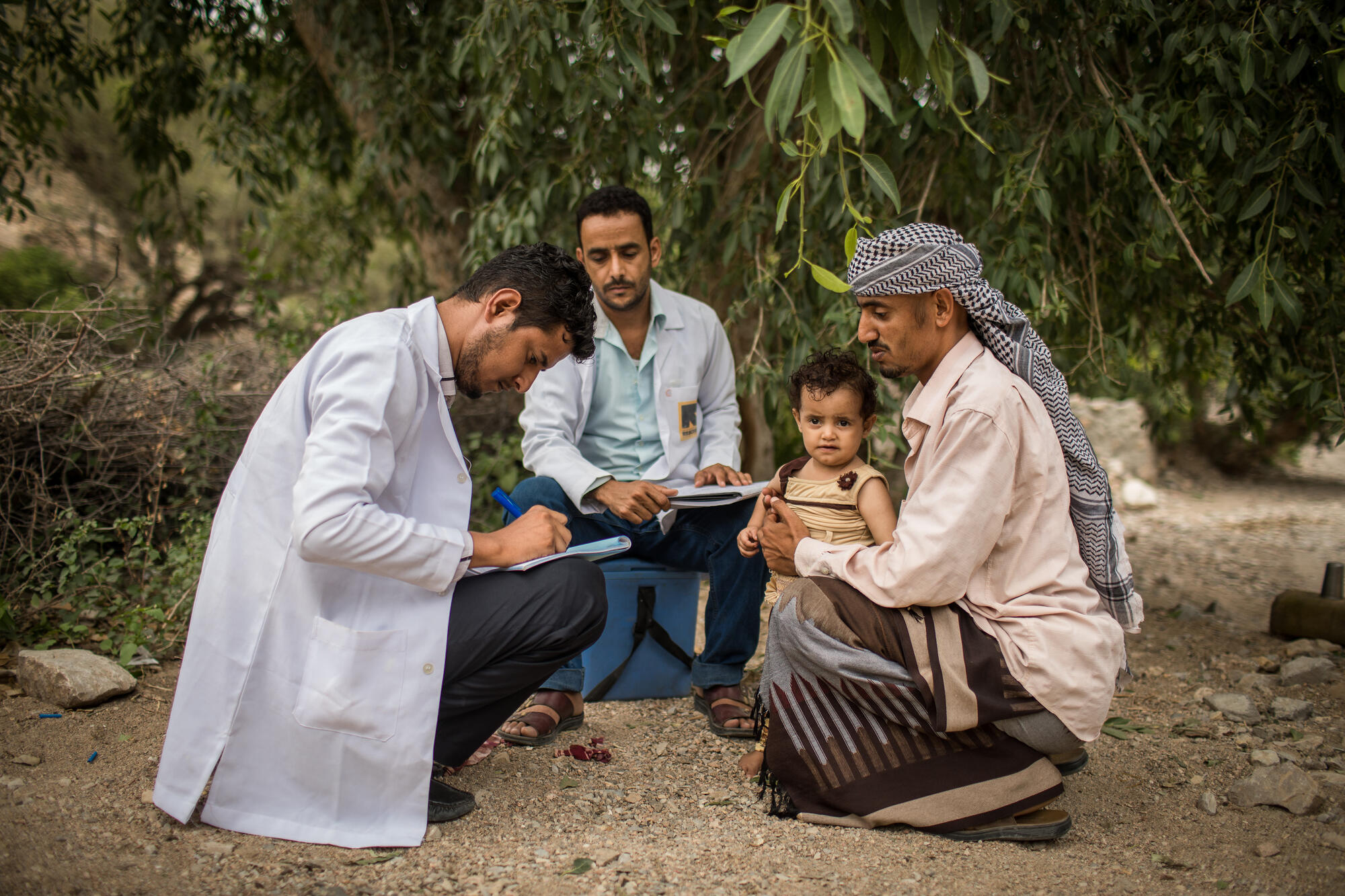 IRC health workers examine a child being held by his father in the village of Mosuk, Yemen