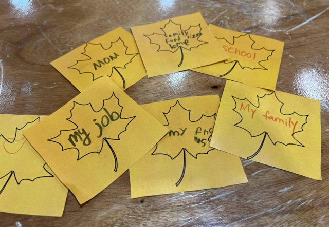 A collection of note cards where Feast attendees wrote what they were thankful for. The note cards are decorated with one large leaf shape outline on each of them.