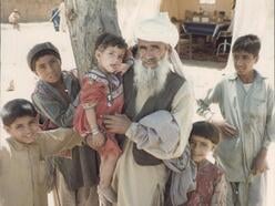 Ein afghanischer Mann mit langem Bart ist umringt von vielen Kindern
