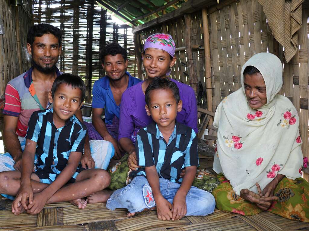 A pregnant woman sits with her husband, two sons, brother, and mother in an IDP shelter in Myanmar.