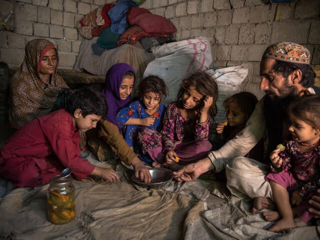 Sajida, her husband Rahmanullah with their children on the floor of their home.