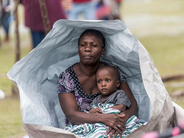 A woman and her son embrace under a tarp in Haiti. The tarp will clearly not provide any longterm protection from the elements.