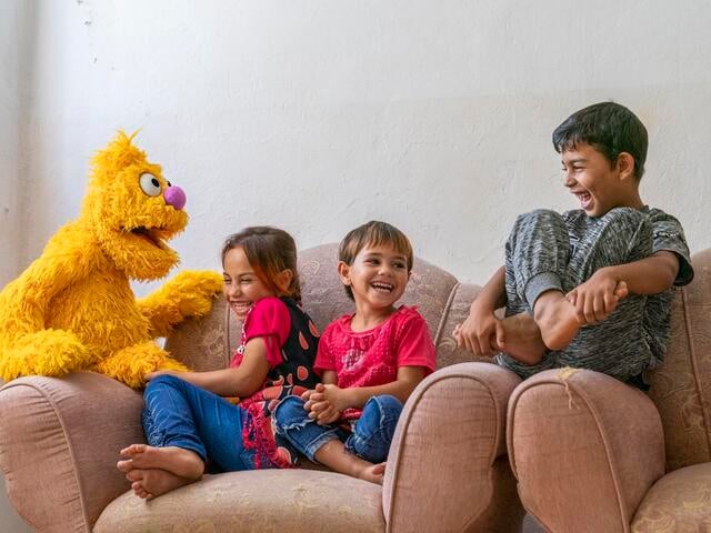 Children sit with new Sesame Street puppet.