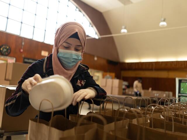 19-year-old Syrian refugee Rania packs containers of donated food into brown paper shopping bags for her neighbors in need in Elizabeth, New Jersey.