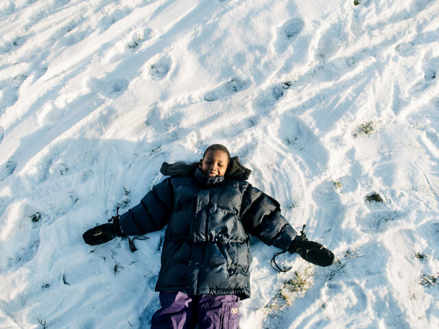 Muhammed creates a snow angel at a park in Boise