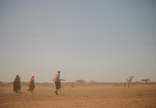 People walk away from the camera, in the background is a beautiful but very dry and barren Ethiopian landscape.
