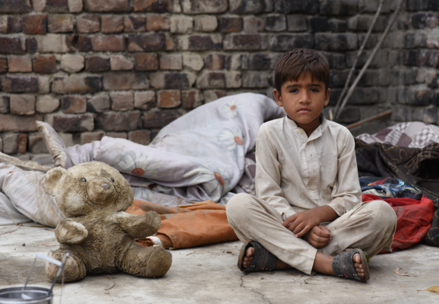 파키스탄 홍수 후 테디베어와 함께 앉아 있는 소년