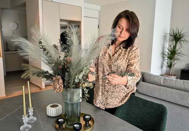 Alisa adjusts a flower centerpiece on the table of an apartment.