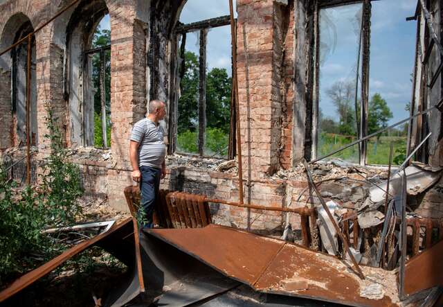 Ein Mann mittleren Alters geht durch die Ruinen eines zerstörten Gebäudes.