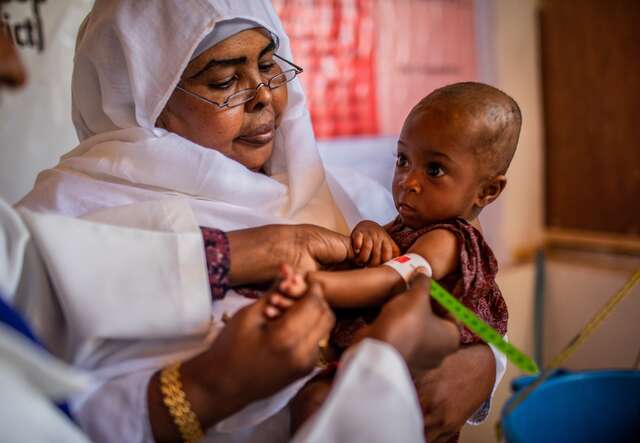 A health workers in Somalia screens a young child for signs of malnutrition.
