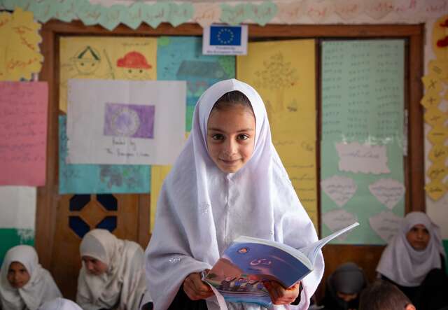A girl poses for a photo and smiles in a classroom in Afghanistan.