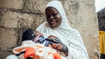 IRC client Hussiena Ibrahim smiles at 7 day old Bello.