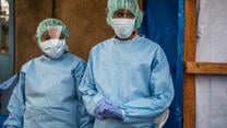 Two IRC staff members, a woman and a man, wear full personal protective equipment (PPE) during an outbreak of Ebola in the Democratic Republic of Congo.