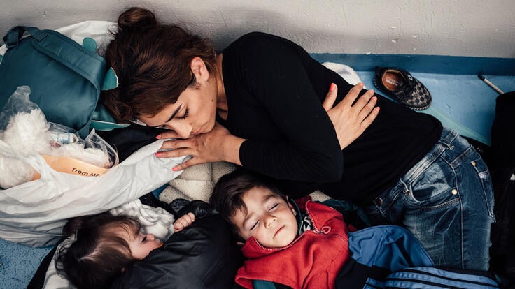 A woman and her two children asleep on a ferry.
