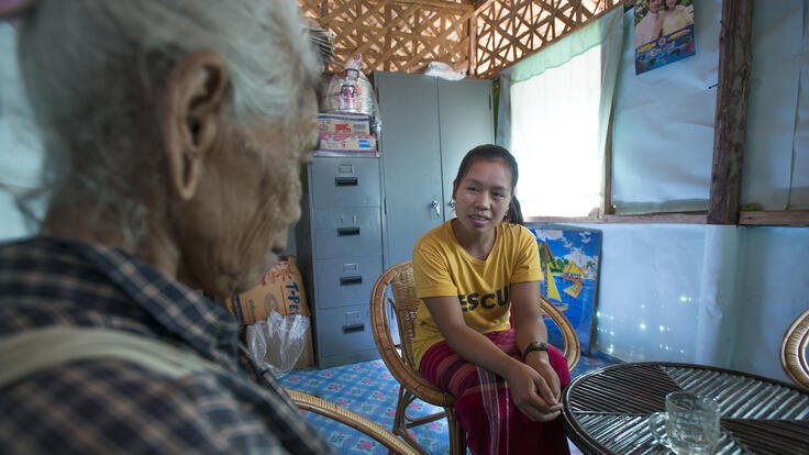 An IRC member seated and speaking to an elderly woman.