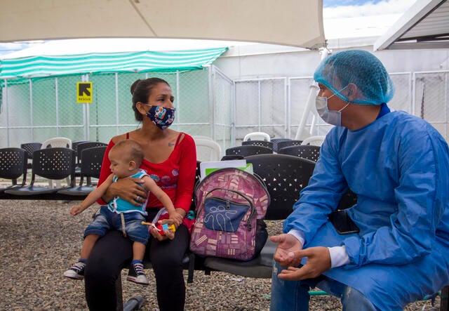 A health worker speaks with a mother holding her baby at a migrant center on the Colombian border with Venezuela, where the IRC is providing medical services.