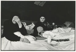 Eine weinende Frau sitzt neben einer andere Frau in einem Zelt
