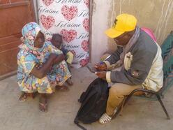 a man looking at his mobile phone sitting with a young woman and a child.