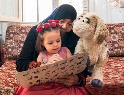 Die neue Sesamstraße Puppe Ma'zooza liest zusammen mit einem Flüchtlingskind in Jordanien