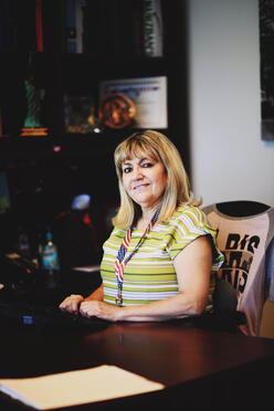 Senior Legal Representative, Nadeana, poses for photo seated behind her desk.