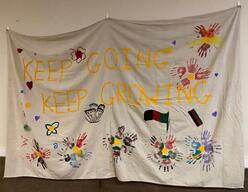 A banner with the words "Keep Going, Keep Growing" written on it with paint