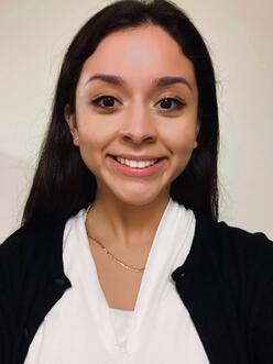 A woman with a white shirt and black sweater smiling 