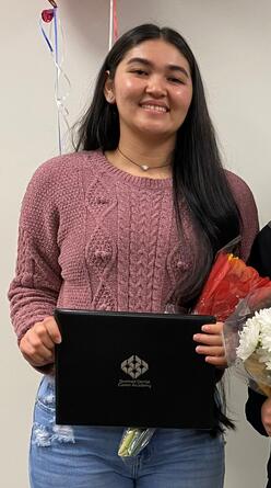 Student Nargis holding a ceritificate of completion and a bouquet of flowers.