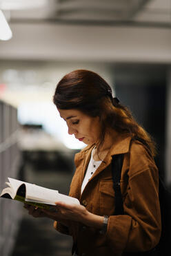 Rahila reading a book at Hayden Library.