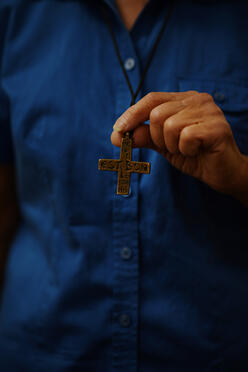 Sister Liane showcasing the cross that she wears around her neck representing the congregation, Sisters of Notre Dame de Namur.