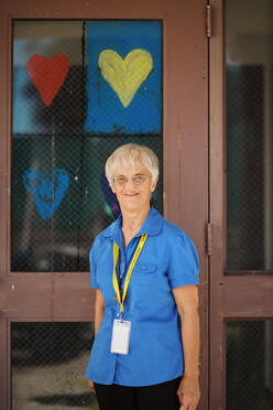 Sister Liane standing in front of the glass doors, with painted hearts, to the Welcome Center 