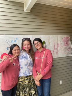 Two female girls from Afghanistan taking a photo with a female member of the Co-Sponsor team