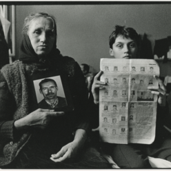  Eine Frau und ihr Enkel in Serbien halten einen Zeitungsausschnitt mit Fotos fünf ihrer Verwandten, die in Bosnien getötet wurden.