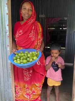 In a coastal region of Bangladesh, Nehar poses for a photo while standing in the entrance of a building next to a child.