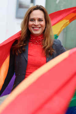 Candy faces the camera, wrapped in a Pride flag.