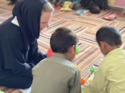 Corina Pfitzner interagiert mit zwei Kindern in Afghanistan