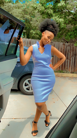 Sandrine leaning against a car while wearing a blue dress.