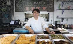 A chef standing in the kitchen with food in front of him