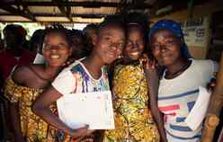 Adolescent girls attend an EAGER session in Tongo Community, Sierra Leone. A group of them pose for a photo together.