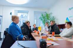 Mehrere Personen sitzen an einem Tisch in einem hellen Büro und führen ein Gespräch in entspannter Atmosphäre.