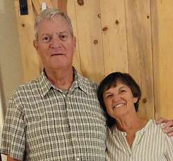 Carol and Bob smile standing next to one another.