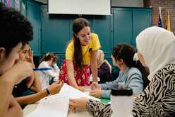 Youth newcomers being supported by IRC staff with homework help.