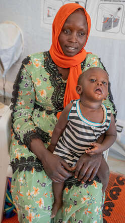 Badriya holds her young child on her lap.