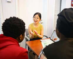 A woman speaking with two clients about her experiences.