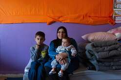 Warda holds her baby, Mohammad, in her lap. Her other son, Wissam, sits next to them on a small mattress.