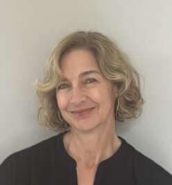 A portrait of Cathy Christensen, shoulder-length sandy blond hair, black blouse, smiling.