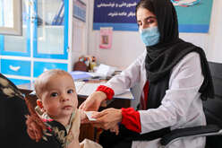 Health worker measures a child's arm to assess malnutrition