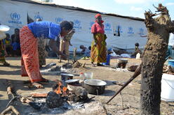 A woman cooks outside of her temporary home in Nyarugusu.