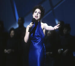 Gloria Estefan singing into a microphone on stage