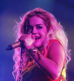 Singer Rita Ora singing into a microphone