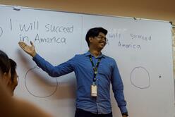 Fadzil Imran Bin Ismail, an RSC cultural orientation trainer, shows his students writing on a whiteboard that reads, "I will succeed in America."